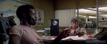 Movie still from “Soylent Green” (1973), directed by Richard Fleischer – Two men sitting at a desk in front of a computer; Medium shot, High angle