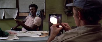 Movie still from “Soylent Green” (1973), directed by Richard Fleischer – A man looking in a mirror while another man looks on; Medium shot, Over the shoulder angle