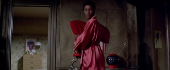 Movie still from “Soylent Green” (1973), directed by Richard Fleischer – A woman in a pink robe holding a red pillow; Medium shot, Low angle