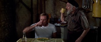 Movie still from “Soylent Green” (1973), directed by Richard Fleischer – A man sitting at a dinner table drinking a beer; Medium shot, High angle
