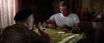 Movie still from “Soylent Green” (1973), directed by Richard Fleischer – Two men sitting at a dinner table eating food; Medium shot, Over the shoulder angle