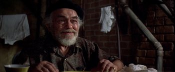 Movie still from “Soylent Green” (1973), directed by Richard Fleischer – An older man wearing a hat and smiling for the camera; Close Up shot, Over the shoulder angle