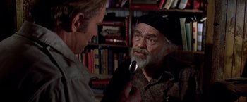 Movie still from “Soylent Green” (1973), directed by Richard Fleischer – A man with a beard is holding a spoon in his mouth while another man looks at him; Close Up shot, Over the shoulder angle