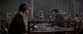 Movie still from “Soylent Green” (1973), directed by Richard Fleischer – Two men working together on a metal grate in an industrial setting; Medium shot, Low angle