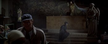 Movie still from “Soylent Green” (1973), directed by Richard Fleischer – A man kneeling down in front of an altar; Wide shot, High angle