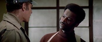 Movie still from “Soylent Green” (1973), directed by Richard Fleischer – A man in a brown sweater talking to another man in a brown hat; Close Up shot, Over the shoulder angle