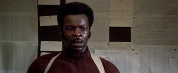 Movie still from “Soylent Green” (1973), directed by Richard Fleischer – A man in a brown sweater is looking at the camera; Close Up shot, Low angle