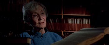 Movie still from “Soylent Green” (1973), directed by Richard Fleischer – An older woman reading a book in front of a bookcase; Close Up shot, Low angle