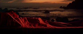 Movie still from “Soylent Green” (1973), directed by Richard Fleischer – A red blanket on top of a beach next to the ocean at sunset; Extreme Wide shot, High angle