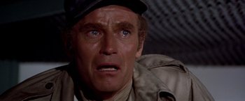 Movie still from “Soylent Green” (1973), directed by Richard Fleischer – A man with a hat and a jacket on looking at the camera; Close Up shot, Over the shoulder angle