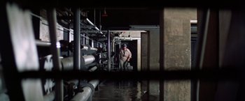 Movie still from “Soylent Green” (1973), directed by Richard Fleischer – A man standing in front of pipes in a building; Wide shot, High angle