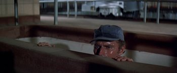 Movie still from “Soylent Green” (1973), directed by Richard Fleischer – A man with a hat is peeking over a wall; Close Up shot, Low angle