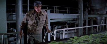 Movie still from “Soylent Green” (1973), directed by Richard Fleischer – A man standing in front of a conveyor belt; Medium shot, Low angle