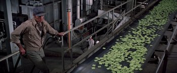 Movie still from “Soylent Green” (1973), directed by Richard Fleischer – A person on a conveyor belt in an industrial setting; Wide shot, High angle