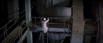 Movie still from “Soylent Green” (1973), directed by Richard Fleischer – A man climbing up a ladder in an industrial setting; Wide shot, Overhead angle