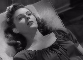 Movie still from “Spellbound” (1945), directed by Alfred Hitchcock – A black - and - white photo of a woman laying on a couch; Close Up shot, High angle