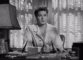Movie still from “Spellbound” (1945), directed by Alfred Hitchcock – A black and white photo of a woman sitting at a desk; Medium shot, Low angle