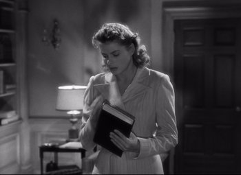 Movie still from “Spellbound” (1945), directed by Alfred Hitchcock – A black and white photo of a woman holding a book; Medium shot, Low angle