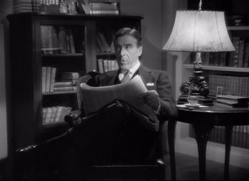 Movie still from “Spellbound” (1945), directed by Alfred Hitchcock – A black and white photo of a man reading a newspaper; Medium shot, Low angle