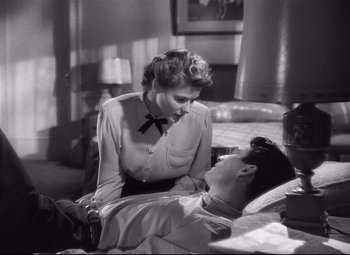 Movie still from “Spellbound” (1945), directed by Alfred Hitchcock – An old photo of a man laying on a bed next to a woman; Medium shot, High angle