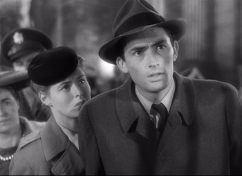 Movie still from “Spellbound” (1945), directed by Alfred Hitchcock – A man and a woman wearing hats in a black - and - white photo; Close Up shot, Low angle