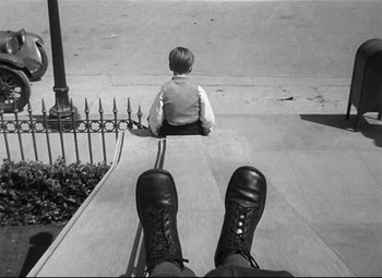Movie still from “Spellbound” (1945), directed by Alfred Hitchcock – A black - and - white photo of a child sitting on the steps; Wide shot, High angle