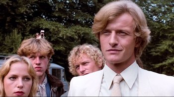 Movie still from “Spetters” (1980), directed by Paul Verhoeven – A man with blonde hair is standing next to two other men; Close Up shot, Low angle