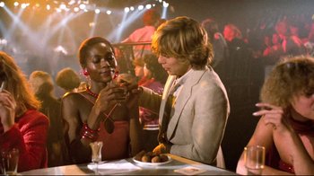 Movie still from “Spetters” (1980), directed by Paul Verhoeven – A man and a woman at a table with food; Medium shot, Over the shoulder angle