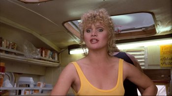Movie still from “Spetters” (1980), directed by Paul Verhoeven – A woman in a yellow tank top is posing for a picture; Close Up shot, Low angle