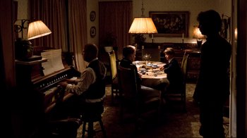 Movie still from “Spetters” (1980), directed by Paul Verhoeven – A group of people sitting around a table playing piano; Wide shot, High angle