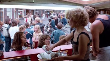 Movie still from “Spetters” (1980), directed by Paul Verhoeven – A group of people sitting at a table with food; Medium shot, Over the shoulder angle
