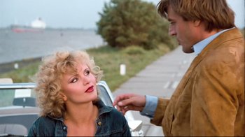 Movie still from “Spetters” (1980), directed by Paul Verhoeven – A man touching a woman's face while she sits on a bench; Medium shot, Over the shoulder angle