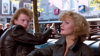 Movie still from “Spetters” (1980), directed by Paul Verhoeven – A woman getting her hair done by a man; Medium shot, Over the shoulder angle