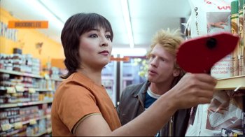 Movie still from “Spetters” (1980), directed by Paul Verhoeven – A man and a woman looking at each other in a store; Medium shot, Over the shoulder angle