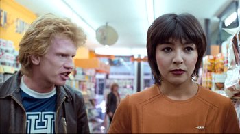 Movie still from “Spetters” (1980), directed by Paul Verhoeven – A man and a woman standing next to each other in a store; Close Up shot, Low angle