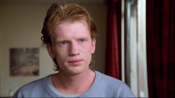 Movie still from “Spetters” (1980), directed by Paul Verhoeven – A man with long blonde hair wearing a blue shirt; Close Up shot, Low angle