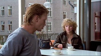 Movie still from “Spetters” (1980), directed by Paul Verhoeven – A man and a woman are sitting at a table; Medium shot, Over the shoulder angle