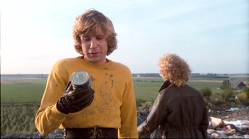 Movie still from “Spetters” (1980), directed by Paul Verhoeven – A young man holding a can of soda while standing next to a woman; Medium shot, Low angle