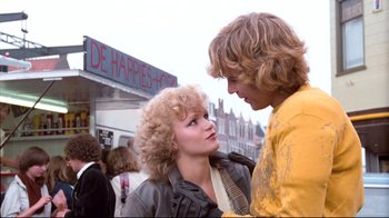 Movie still from “Spetters” (1980), directed by Paul Verhoeven – A man and a woman standing next to each other on the street; Medium shot, Low angle