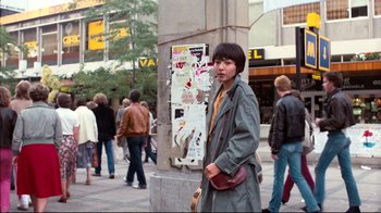 Movie still from “Spetters” (1980), directed by Paul Verhoeven – A man standing next to a pole on the sidewalk; Medium shot, Low angle