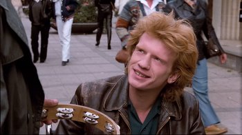 Movie still from “Spetters” (1980), directed by Paul Verhoeven – A young man with red curly hair holding a guitar; Close Up shot, Low angle
