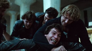 Movie still from “Spetters” (1980), directed by Paul Verhoeven – A group of young men laughing and playing around; Medium shot, High angle