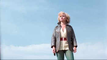 Movie still from “Spetters” (1980), directed by Paul Verhoeven – A woman standing in a field wearing a leather jacket; Medium shot, Low angle