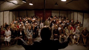 Movie still from “Spetters” (1980), directed by Paul Verhoeven – A crowd of people sitting and standing in front of a man; Wide shot, High angle