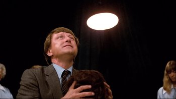 Movie still from “Spetters” (1980), directed by Paul Verhoeven – A man in a suit and tie holding a cat; Close Up shot, Low angle