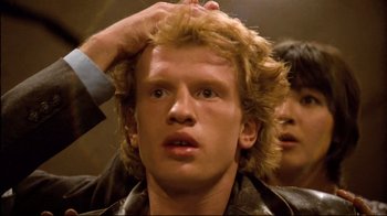 Movie still from “Spetters” (1980), directed by Paul Verhoeven – A man with a messy hair style is getting his hair combed; Close Up shot, Low angle