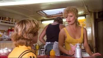 Movie still from “Spetters” (1980), directed by Paul Verhoeven – A woman in a yellow shirt is talking to a man in a yellow shirt; Medium shot, Over the shoulder angle