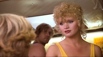 Movie still from “Spetters” (1980), directed by Paul Verhoeven – A woman in a yellow top is in front of two men; Close Up shot, Over the shoulder angle