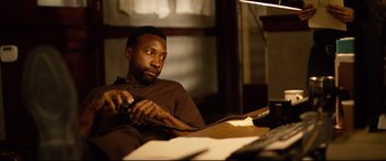 Movie still from “Spiral” (2021), directed by Darren Lynn Bousman – A man sitting in front of a computer desk; Medium shot, High angle