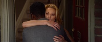 Movie still from “Spiral” (2021), directed by Darren Lynn Bousman – A woman is hugging a man in a suit; Close Up shot, Over the shoulder angle